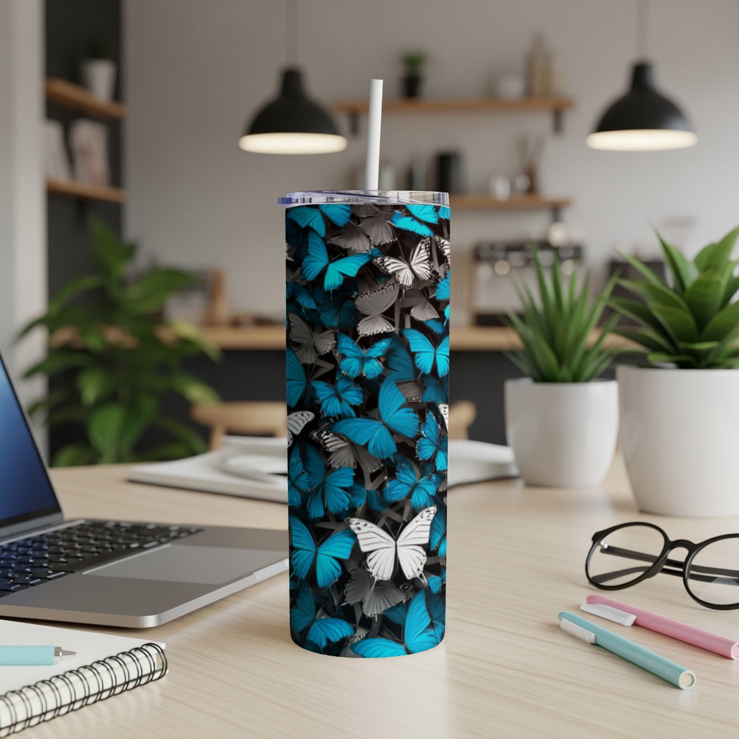 Tall tumbler with blue and gray butterflies on a desk.