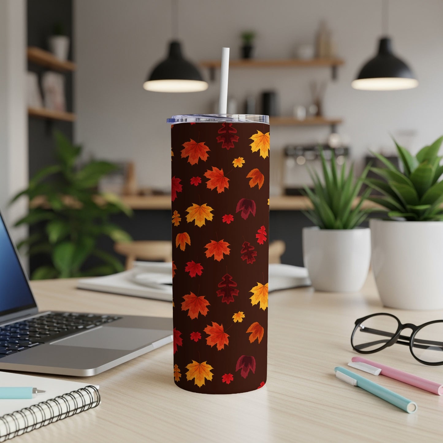 Brown tumbler with a falling autumn leaves pattern and white straw.