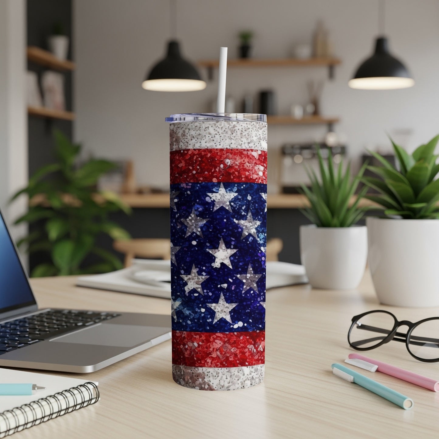 Glittery American flag tumbler with a white straw, on a desk.