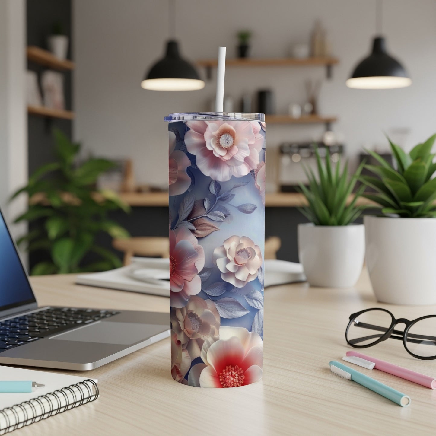 Floral pattern tumbler with straw on a desk.