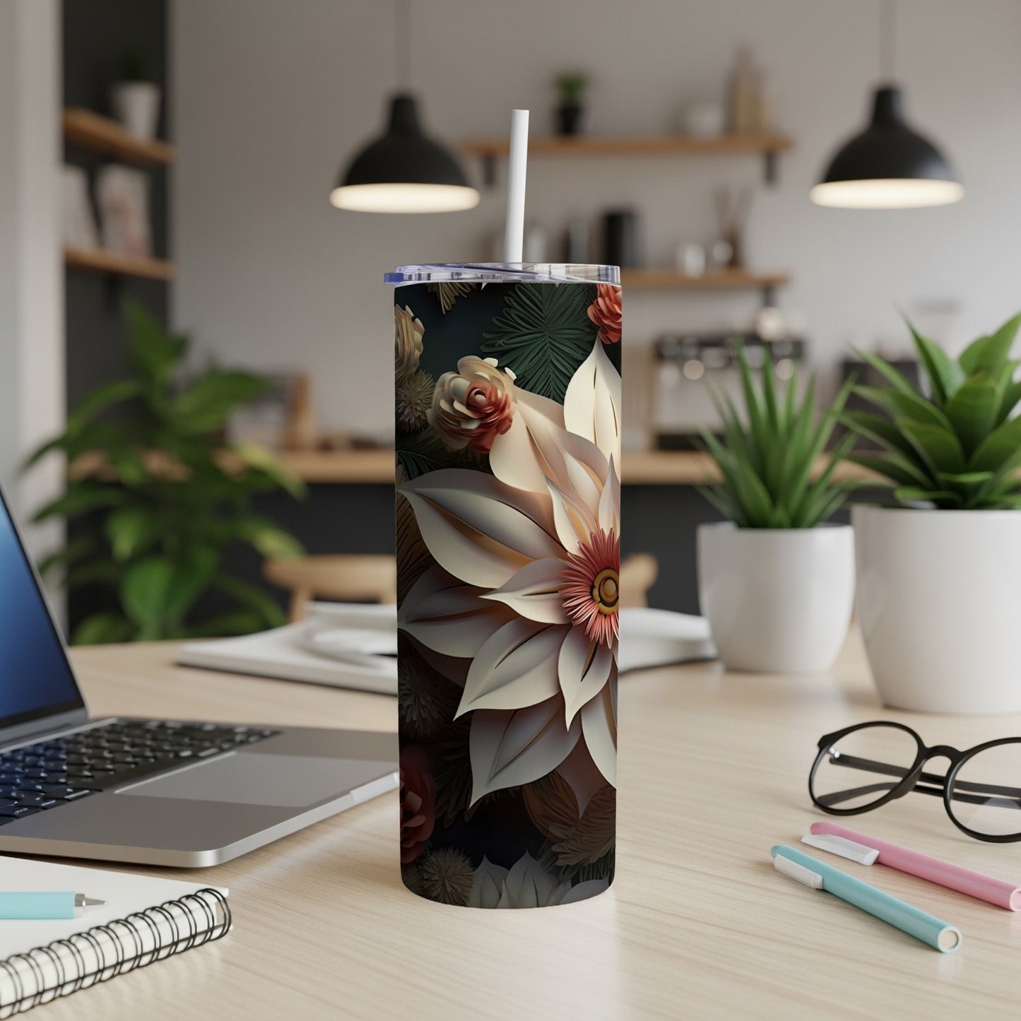 Tall floral tumbler with a white straw on a desk next to a laptop.