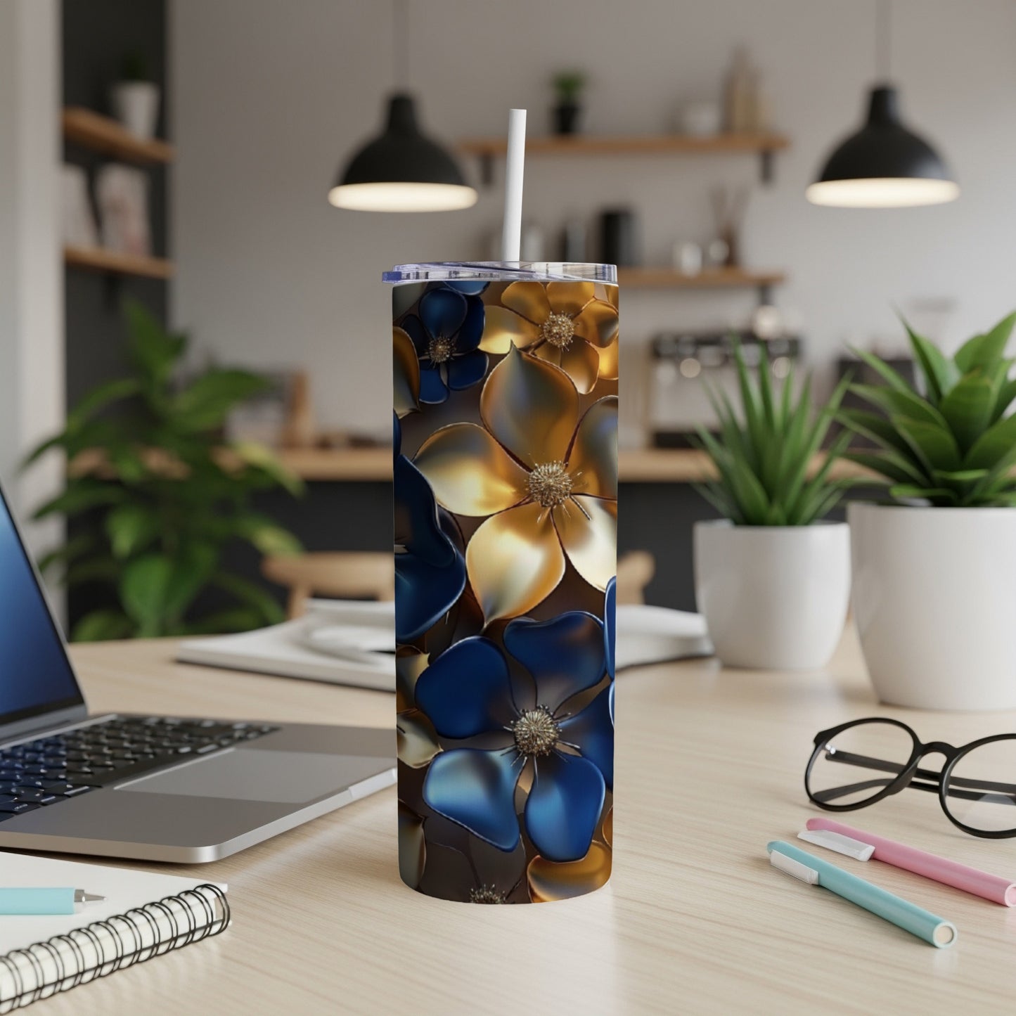 Blue and gold floral tumbler with straw on a desk.