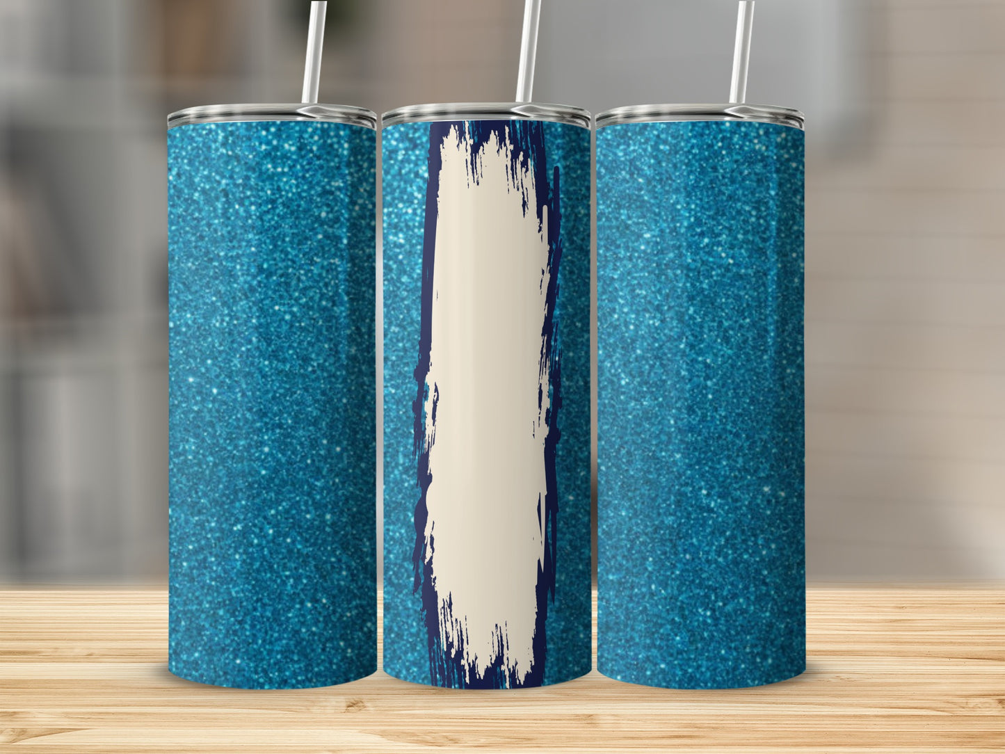 Three sparkly blue tumblers, one with a cream and navy brushstroke design.