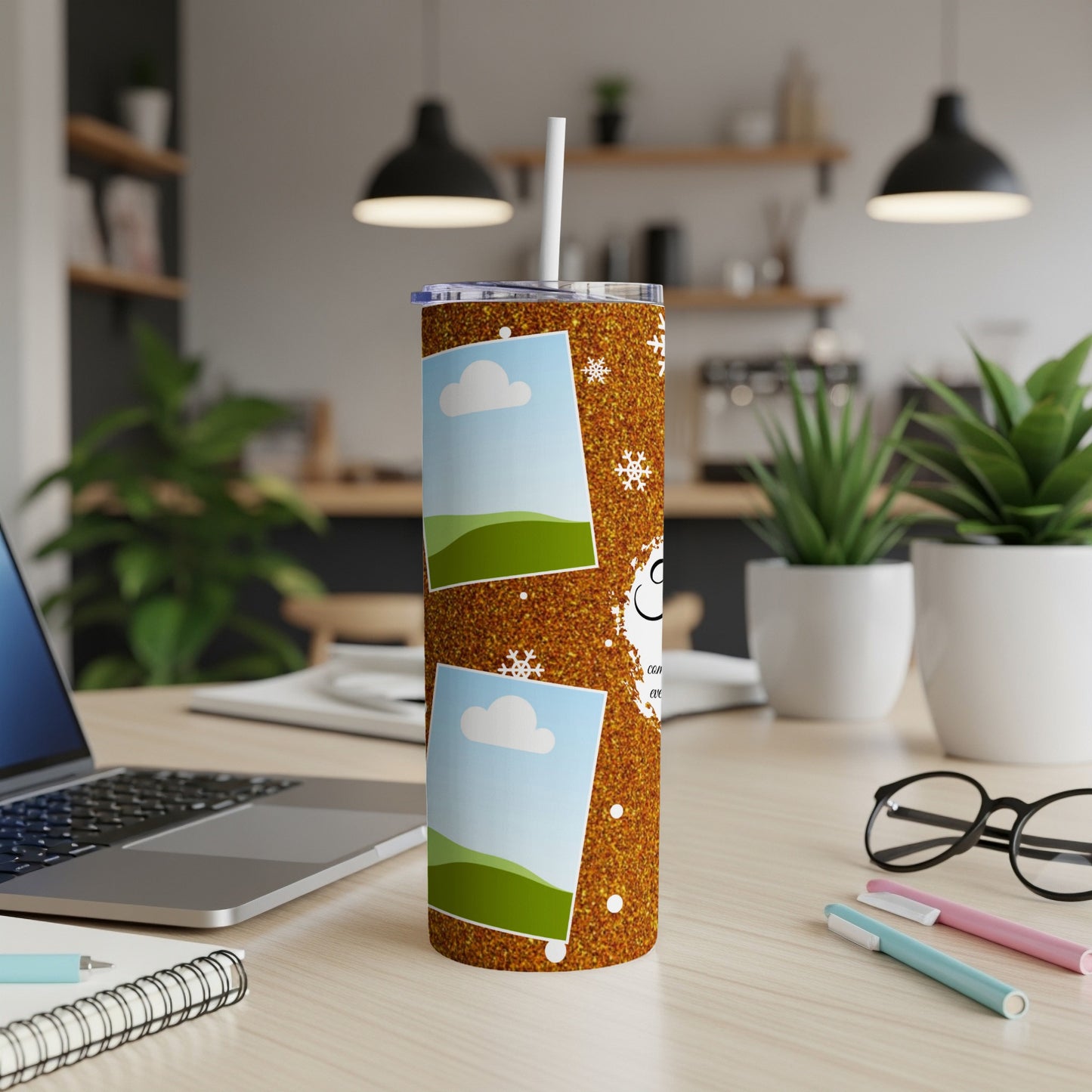 Glitter tumbler with two photo frames and snowflakes on a desk.