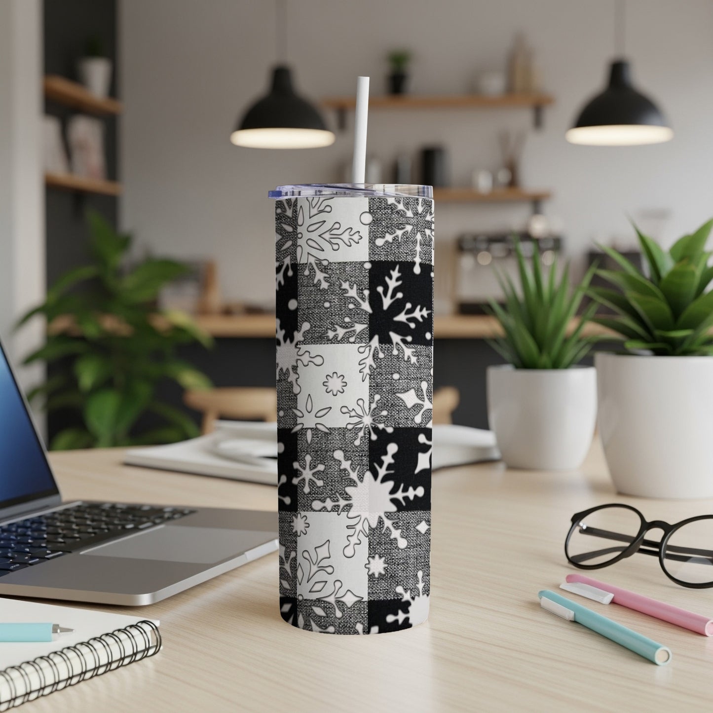 Black and white snowflake buffalo plaid tumbler with straw on desk.