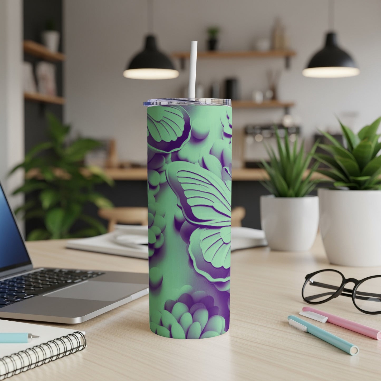Green tumbler with purple butterfly and floral pattern on a desk.