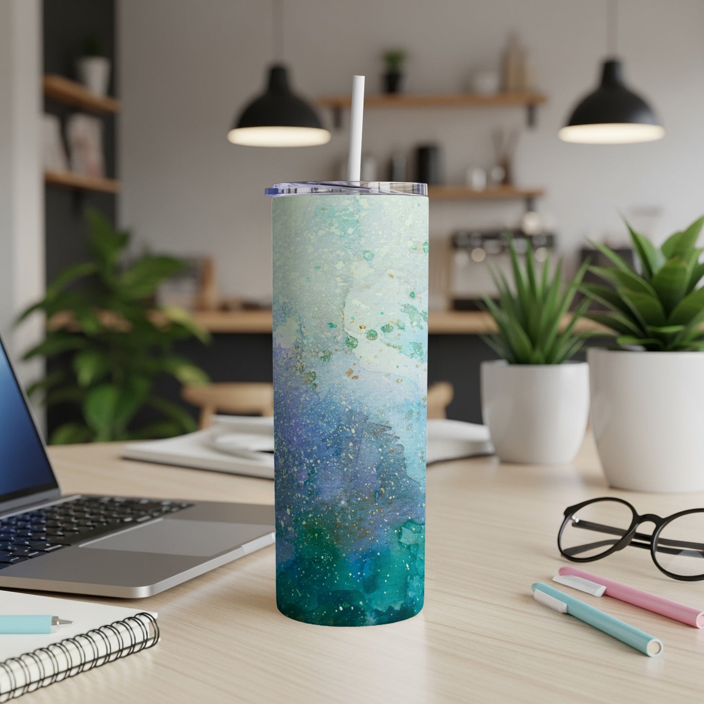 Abstract watercolor tumbler with lid and straw on desk.