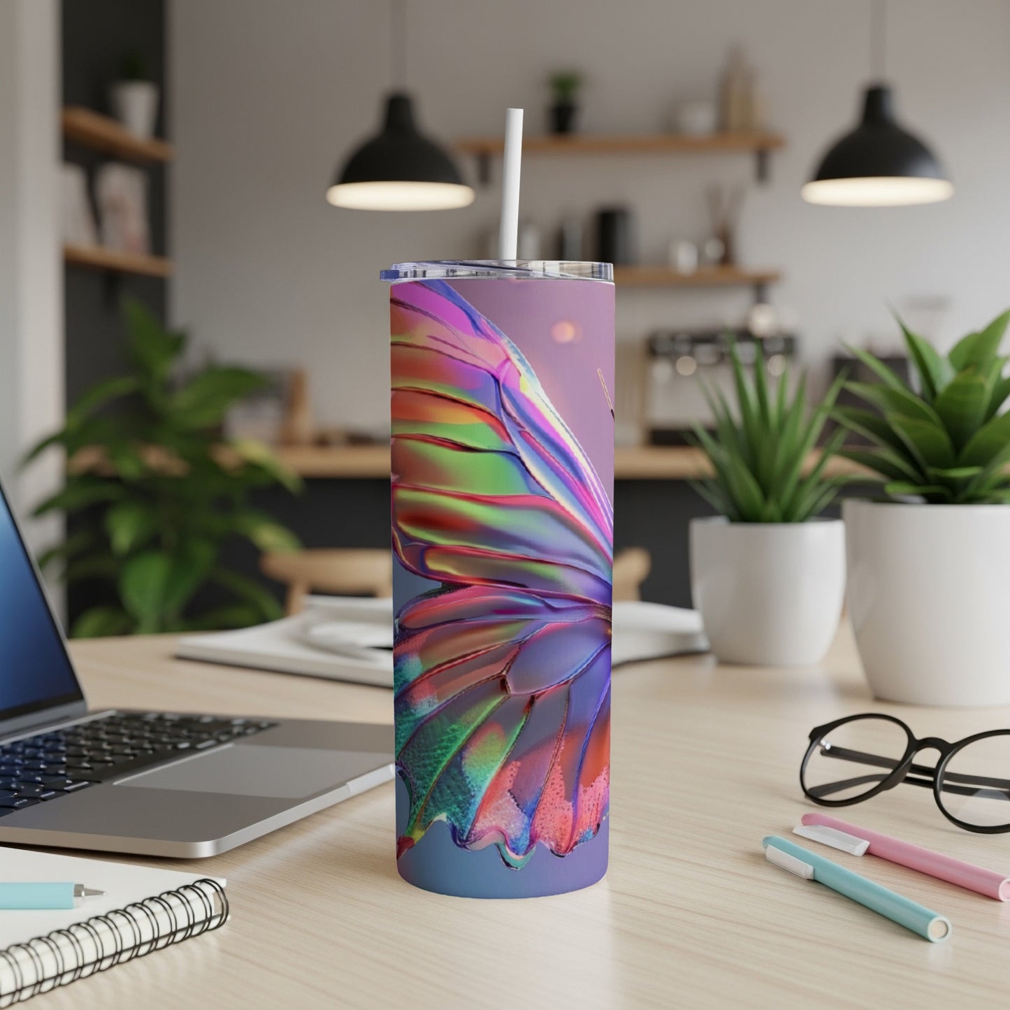 Iridescent butterfly wing tumbler with straw on desk.