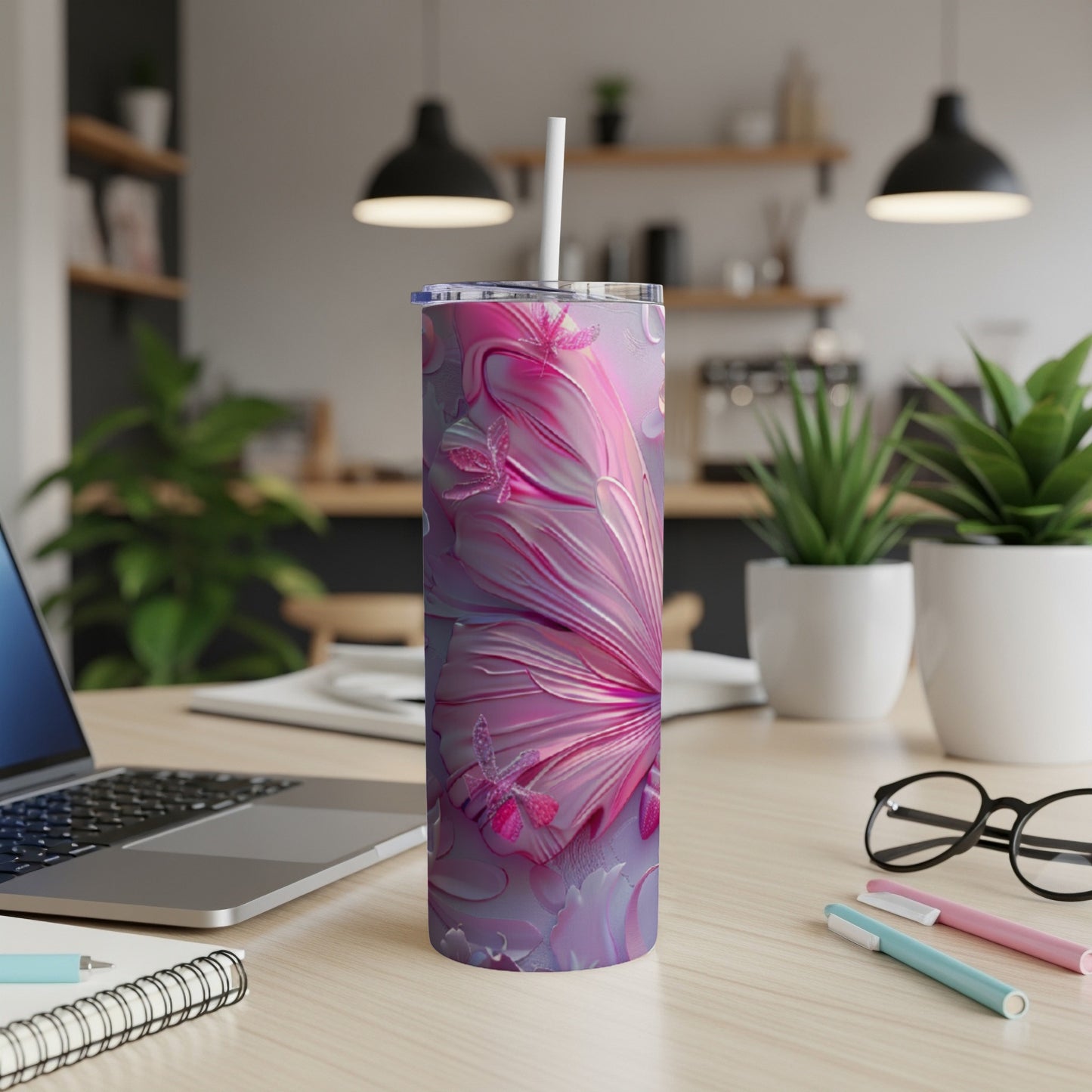 Pink butterfly tumbler with straw on a desk with a laptop and pens.