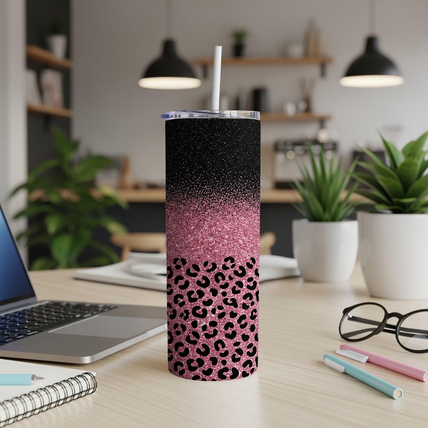 Black and pink glitter cheetah print tumbler with straw on desk.
