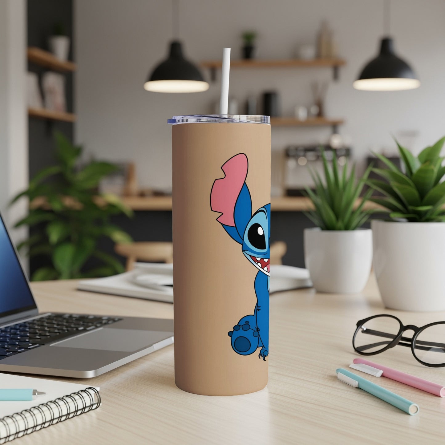 Blue Stitch character on a tan tumbler with straw, on a desk.