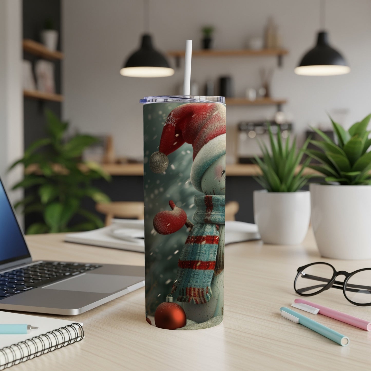 Snowman tumbler with red hat and scarf, on a desk.