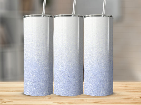 Three white tumblers with blue glitter ombre design on a wooden surface.