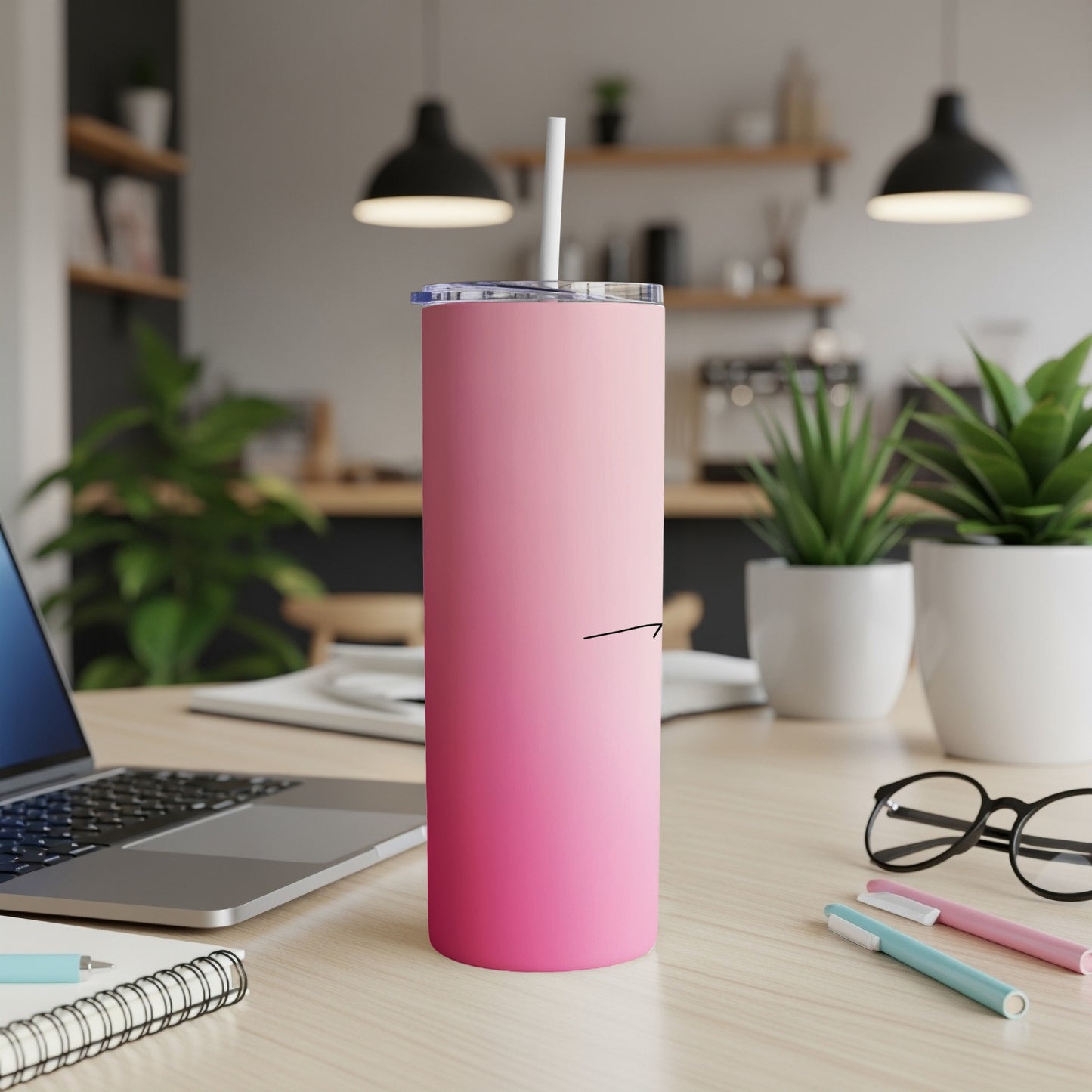 Pink gradient skinny tumbler with straw on a desk.