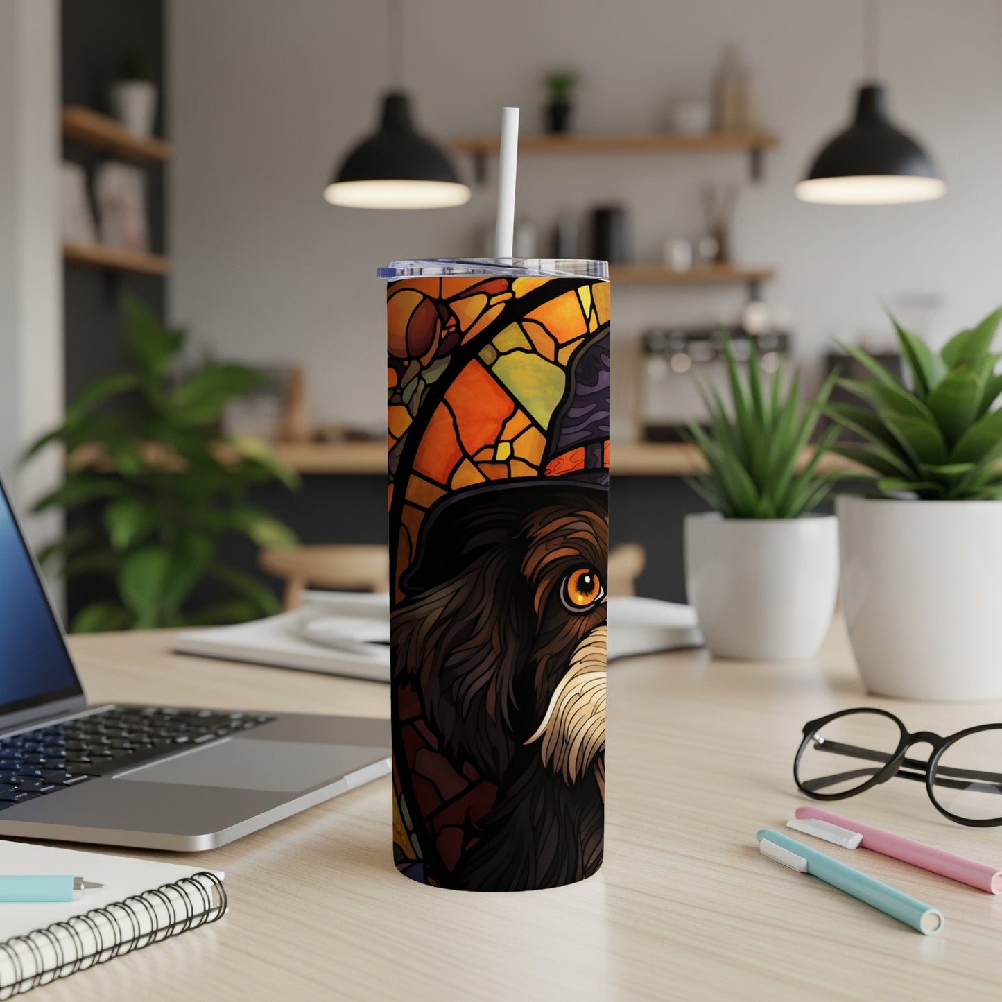 Stained glass dog tumbler with a witch's hat on a desk.