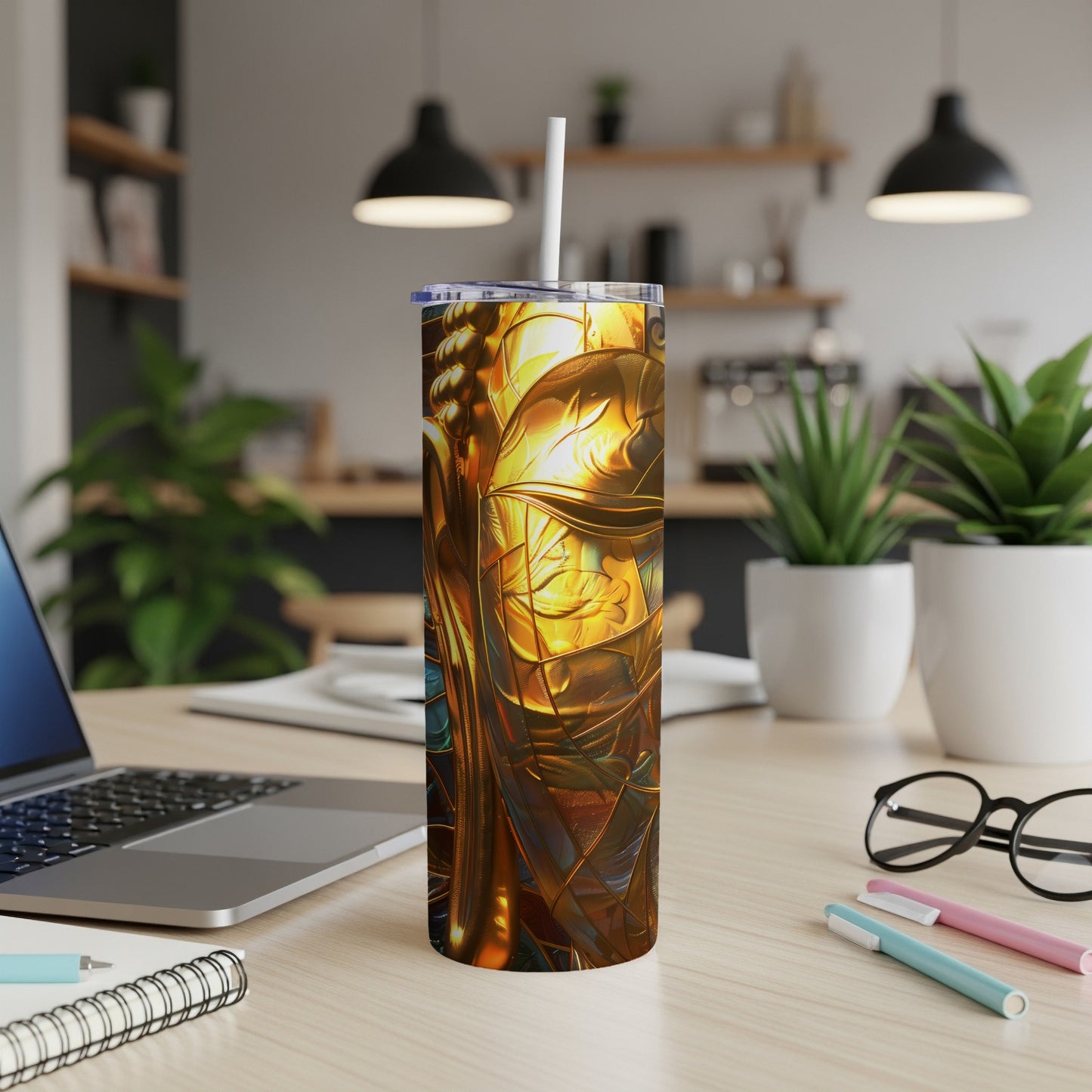 Gold and blue abstract art tumbler with straw on desk.