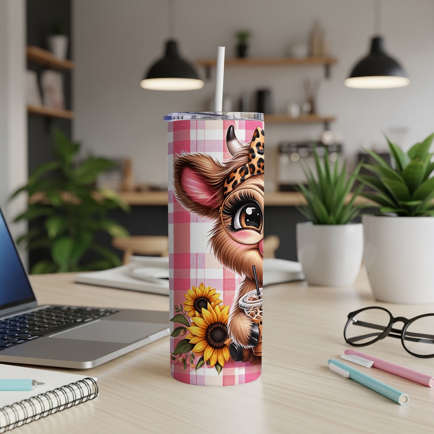 Pink gingham tumbler with cow face and sunflowers, straw in coffee cup.