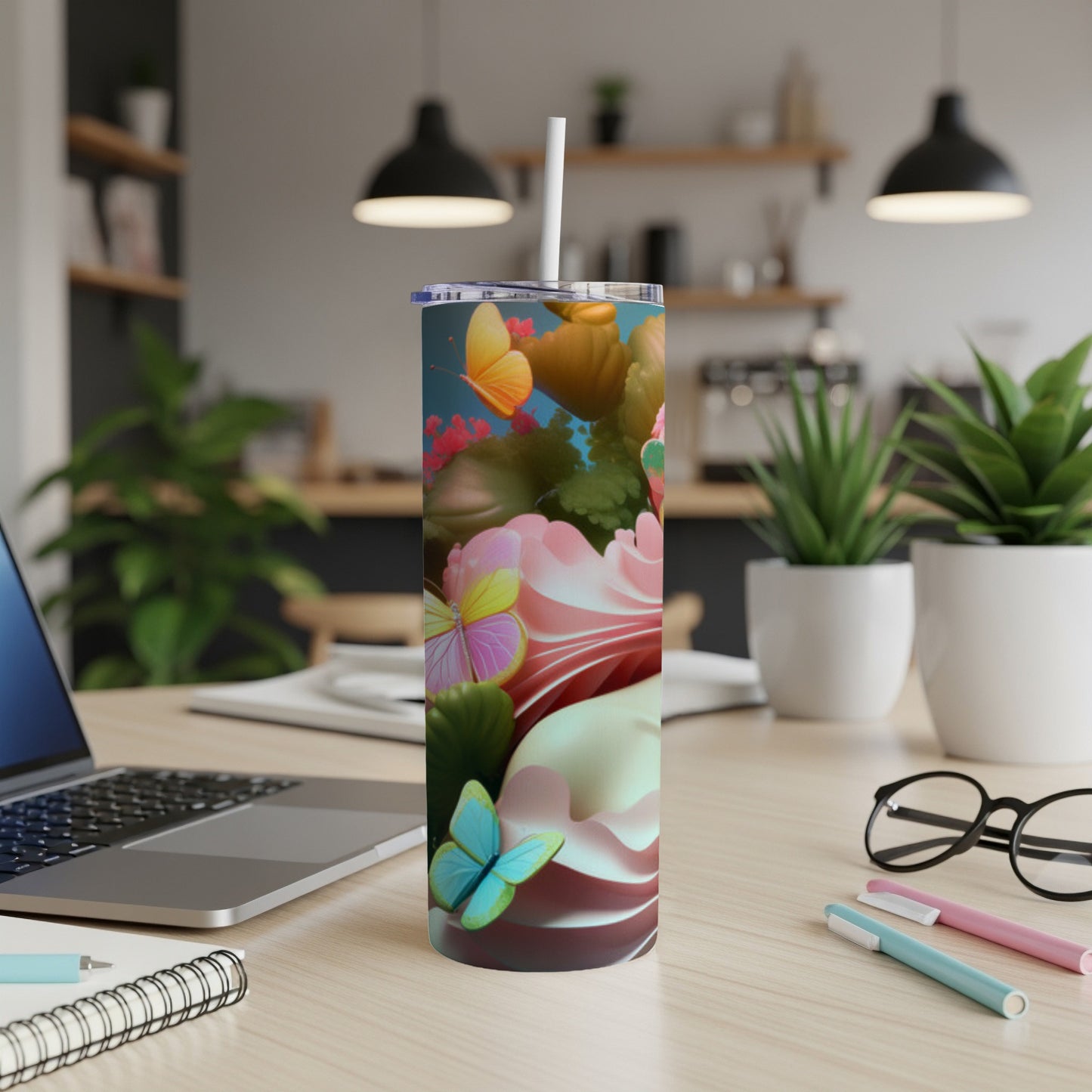 Tall tumbler with butterflies and pink floral design on desk.