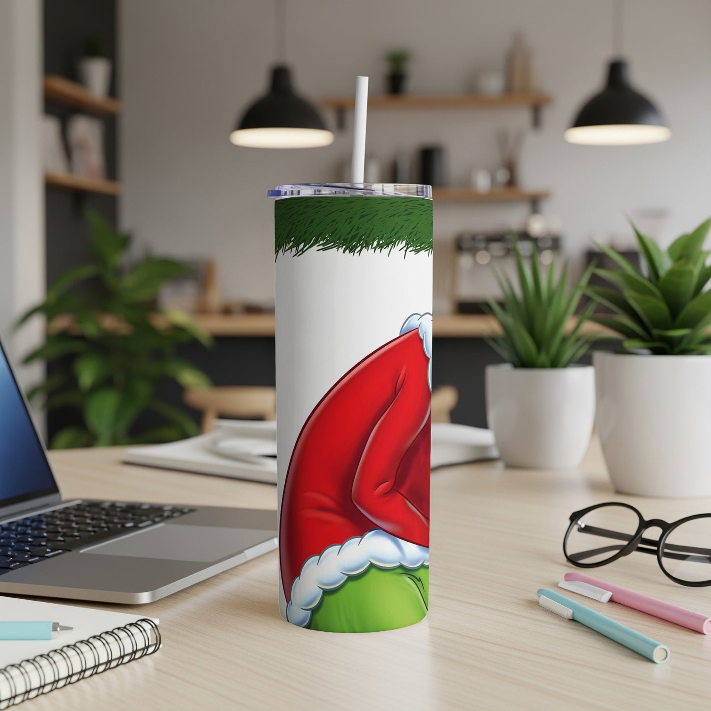 Grinch in Santa hat on a white tumbler with straw, with a laptop and office supplies.