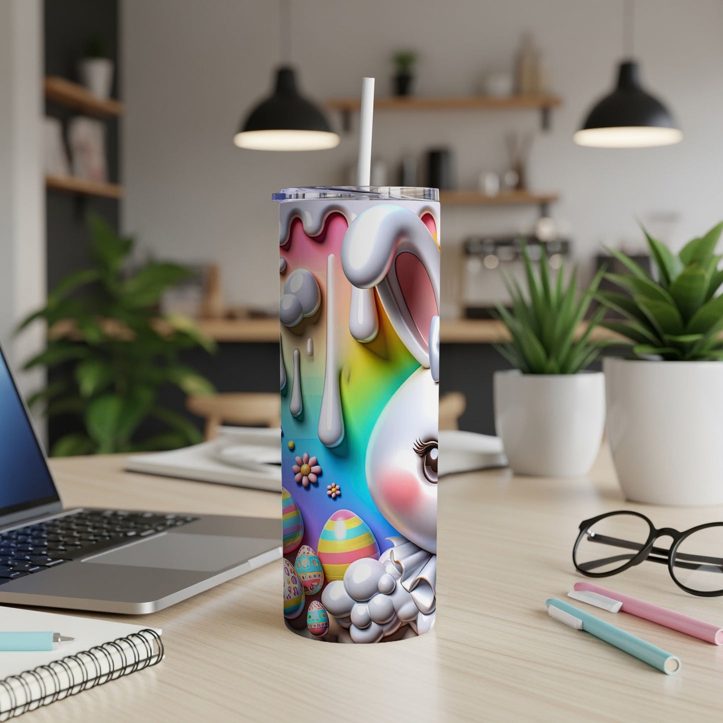 Easter bunny and eggs design on a tumbler with straw, laptop and pens on desk.