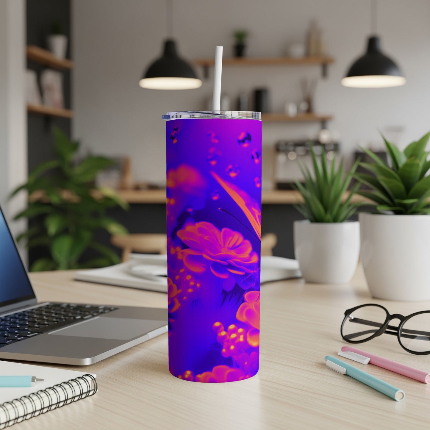 Purple tumbler with vibrant floral pattern and straw on a desk.