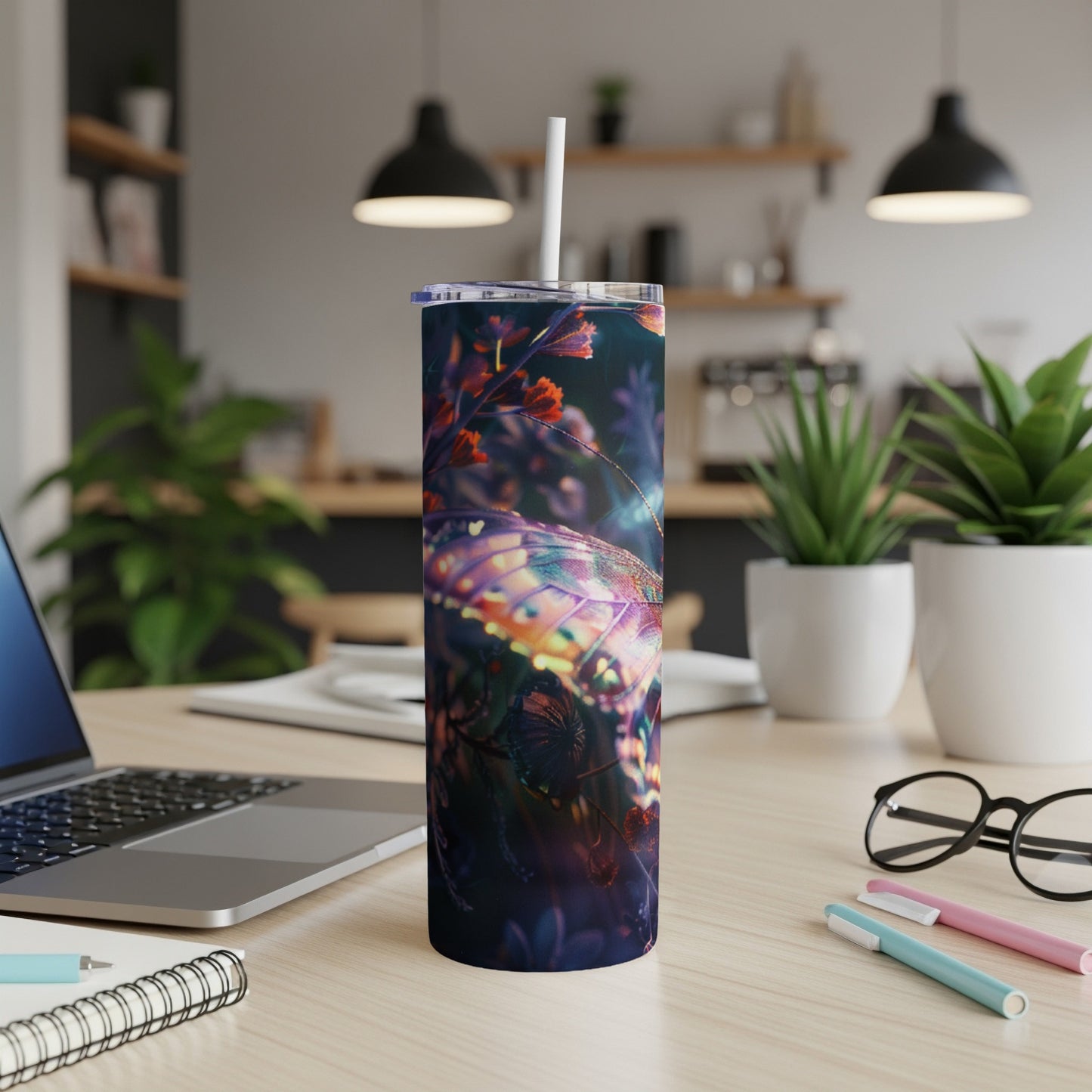 Dark tumbler with iridescent butterfly wings design on a desk.