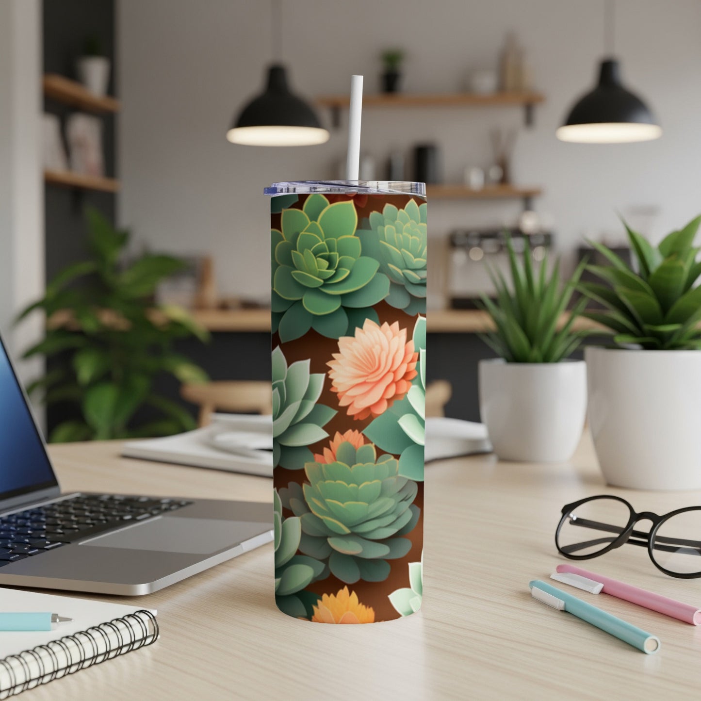 Brown tumbler with succulent floral pattern, straw, on a desk.