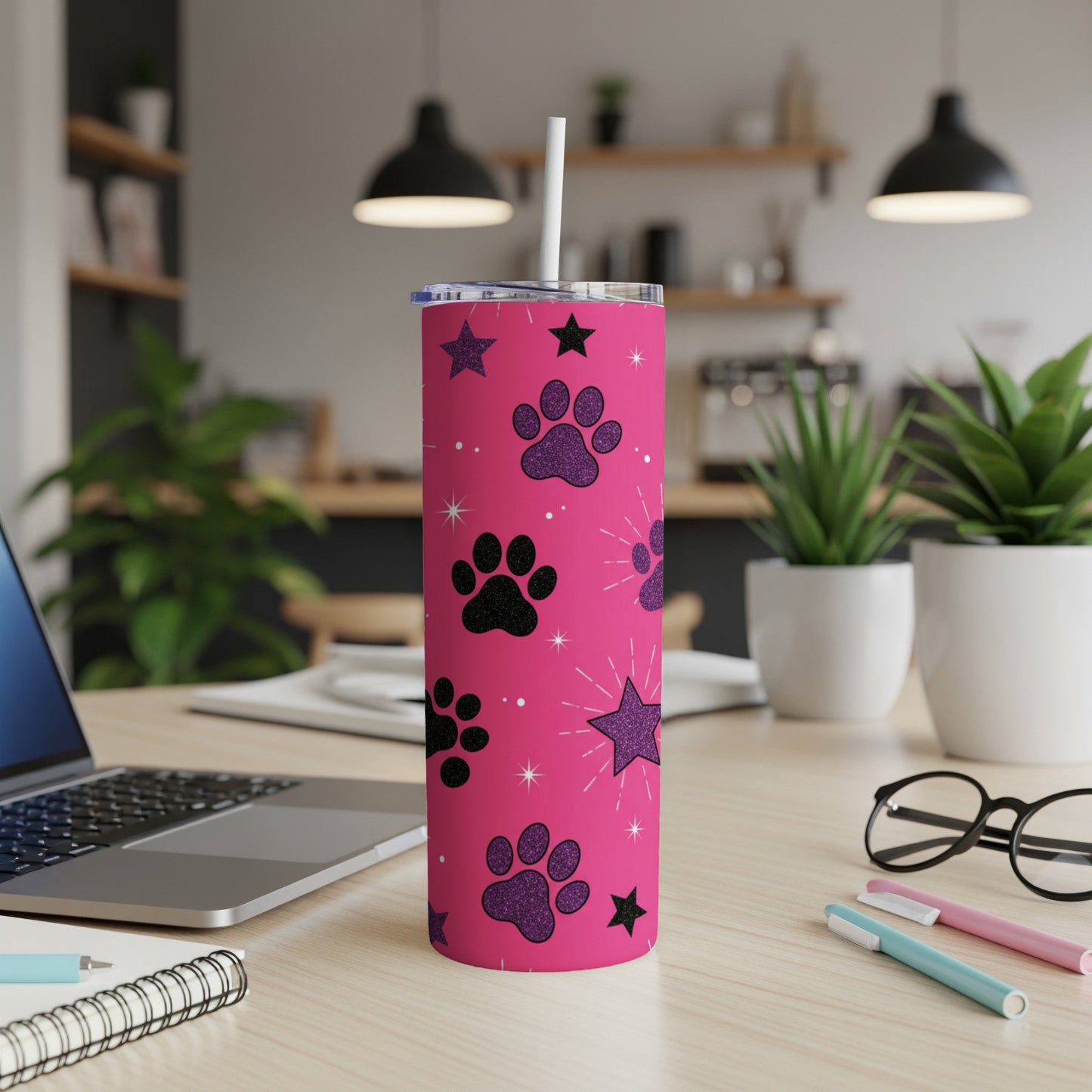 Pink tumbler with black paw prints and glitter stars, a white straw inserted.