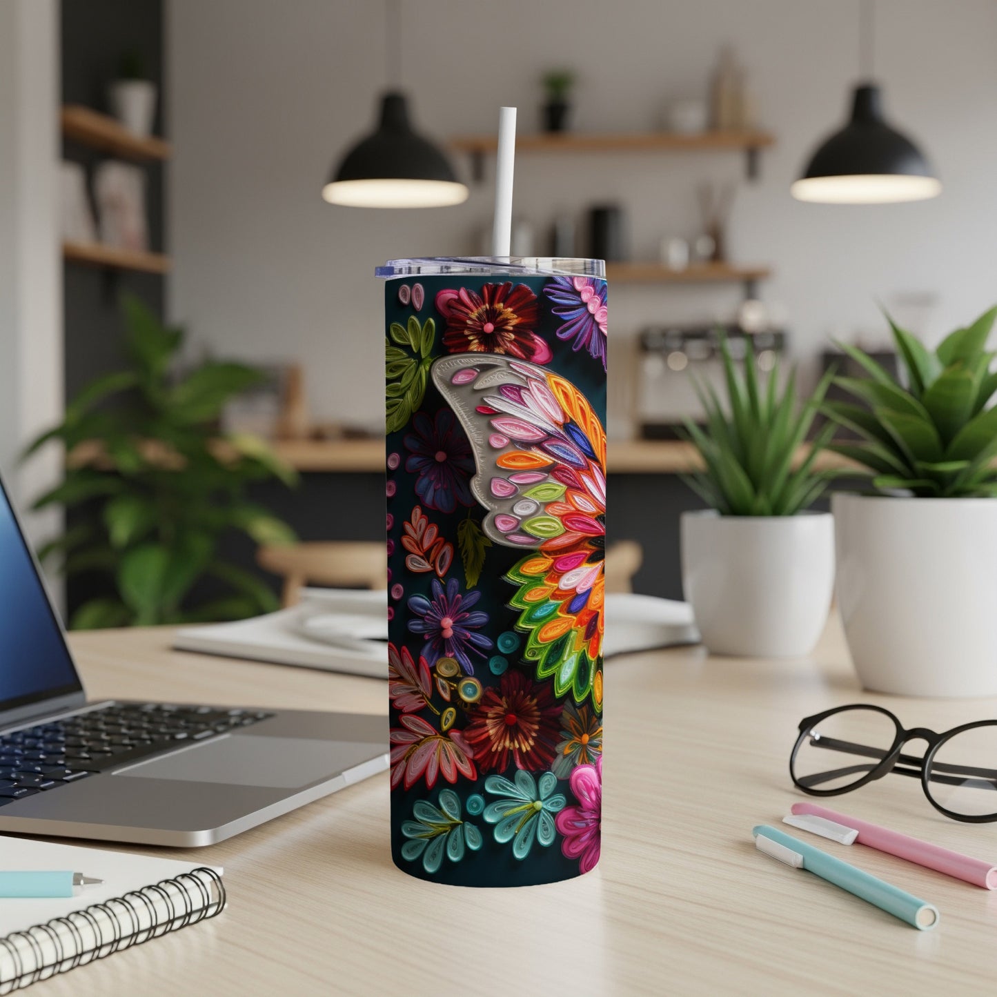 Tall floral tumbler with butterfly wing design and straw on a desk.