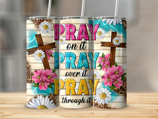 Tumbler with "Pray on it, pray over it, pray through it" text and floral cross design.