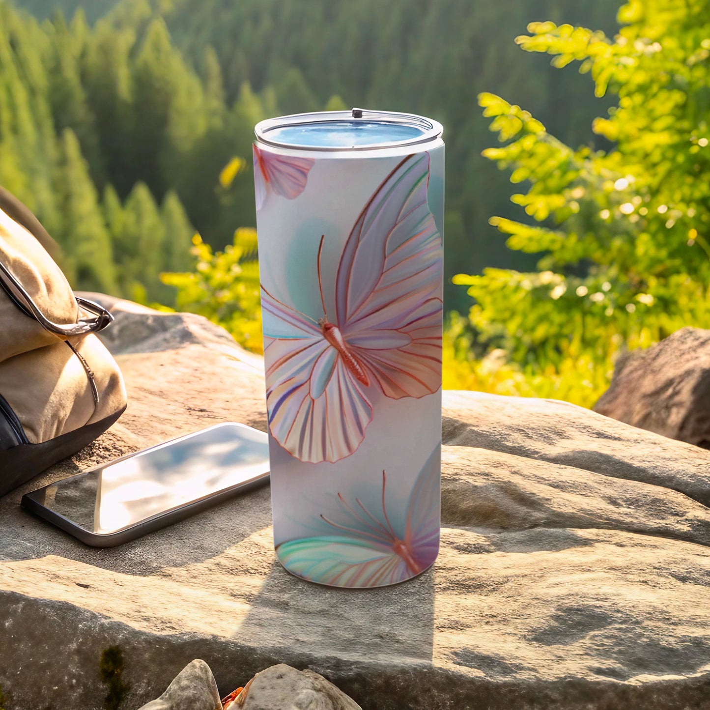 White tumbler with pastel butterfly pattern, sits on rocks outdoors.
