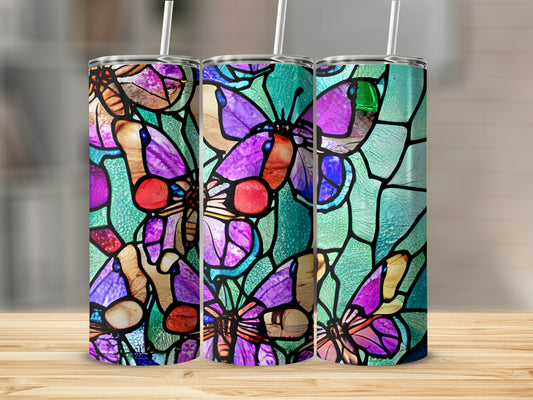 Three tumblers with stained glass butterfly designs on a wooden surface.