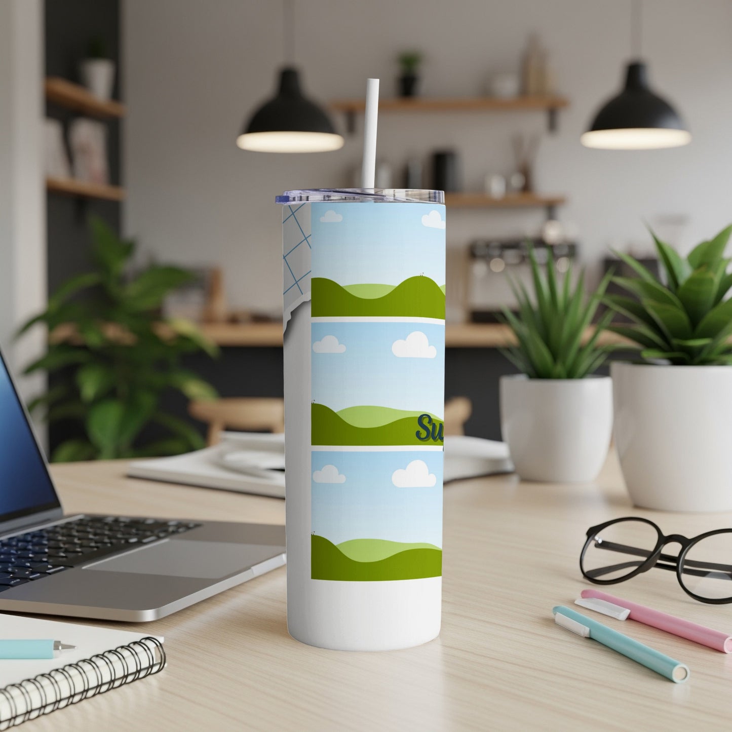 White tumbler with a sky and green hills design, featuring the word "Su".