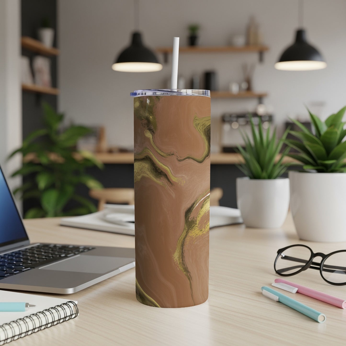 Brown and gold marbled insulated tumbler with straw on desk.