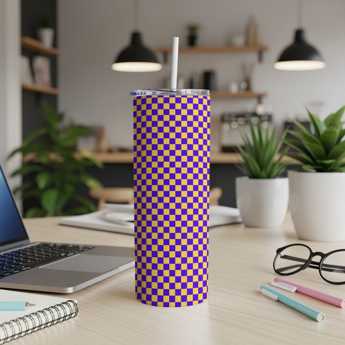 Purple and yellow checkerboard tumbler with white straw on desk.