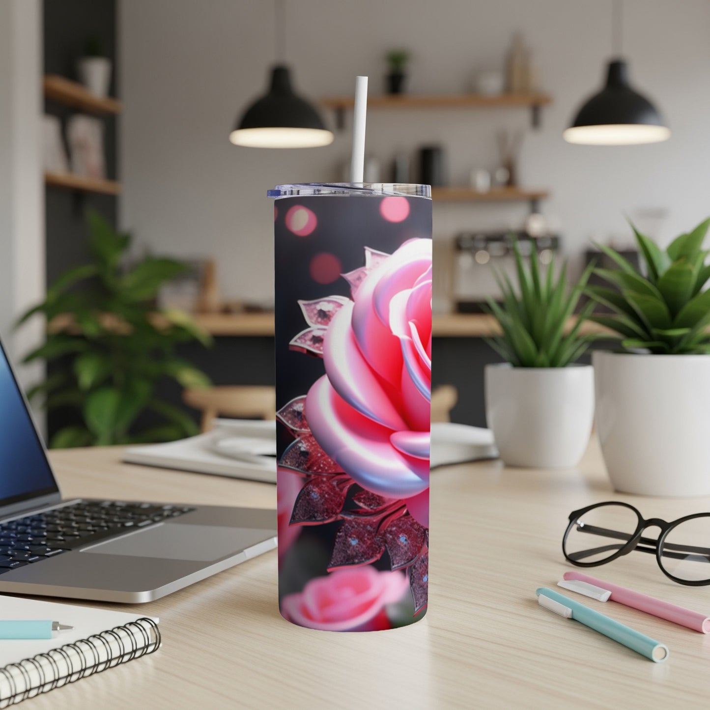 Tumbler with a pink rose design and sparkles, on a desk.
