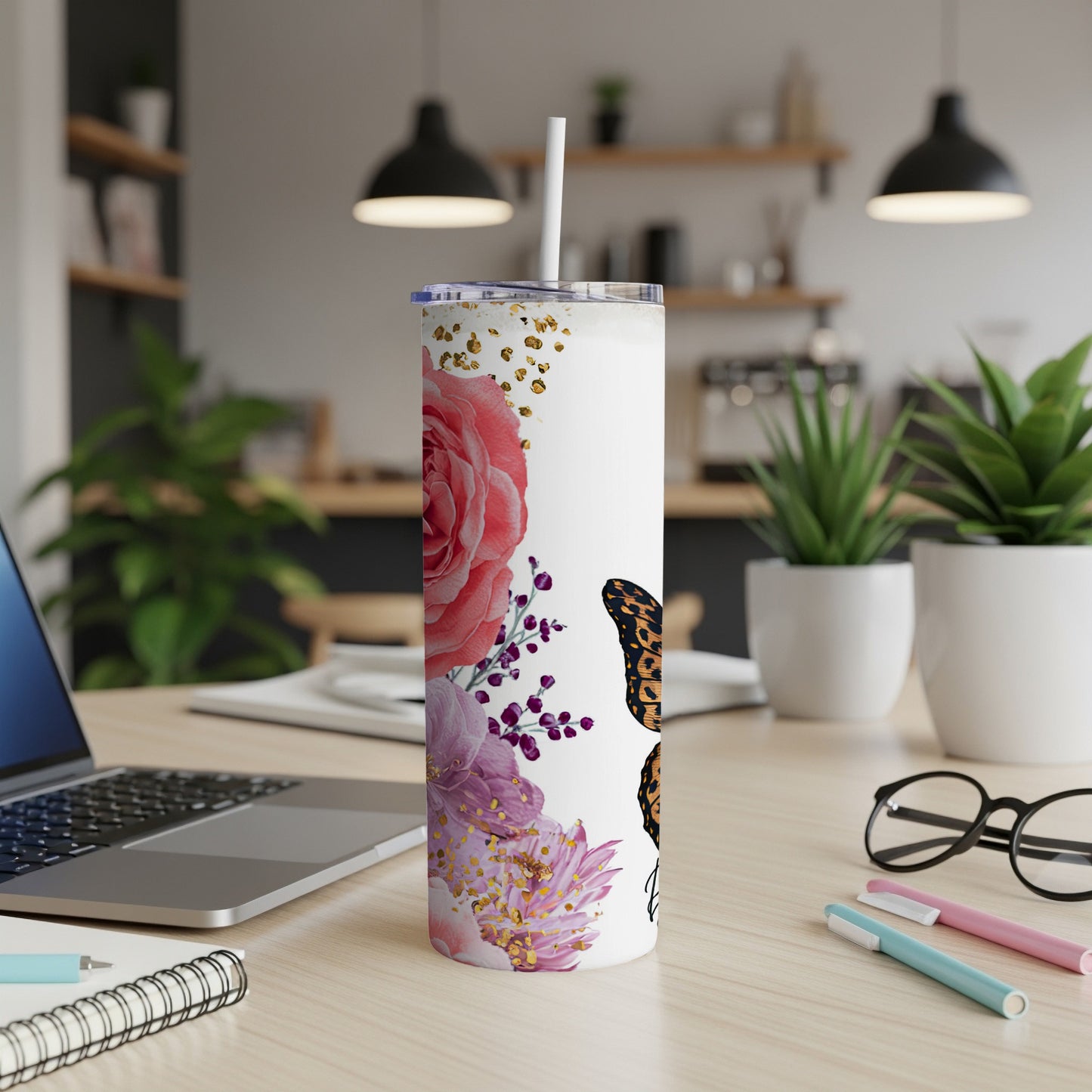 White tumbler with floral and butterfly design, on a desk.