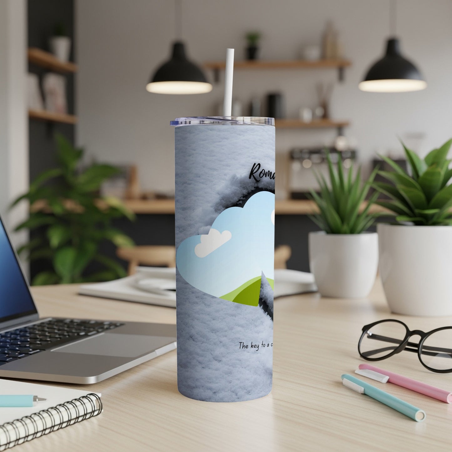 A white tumbler with a blue sky and green hill design and text.
