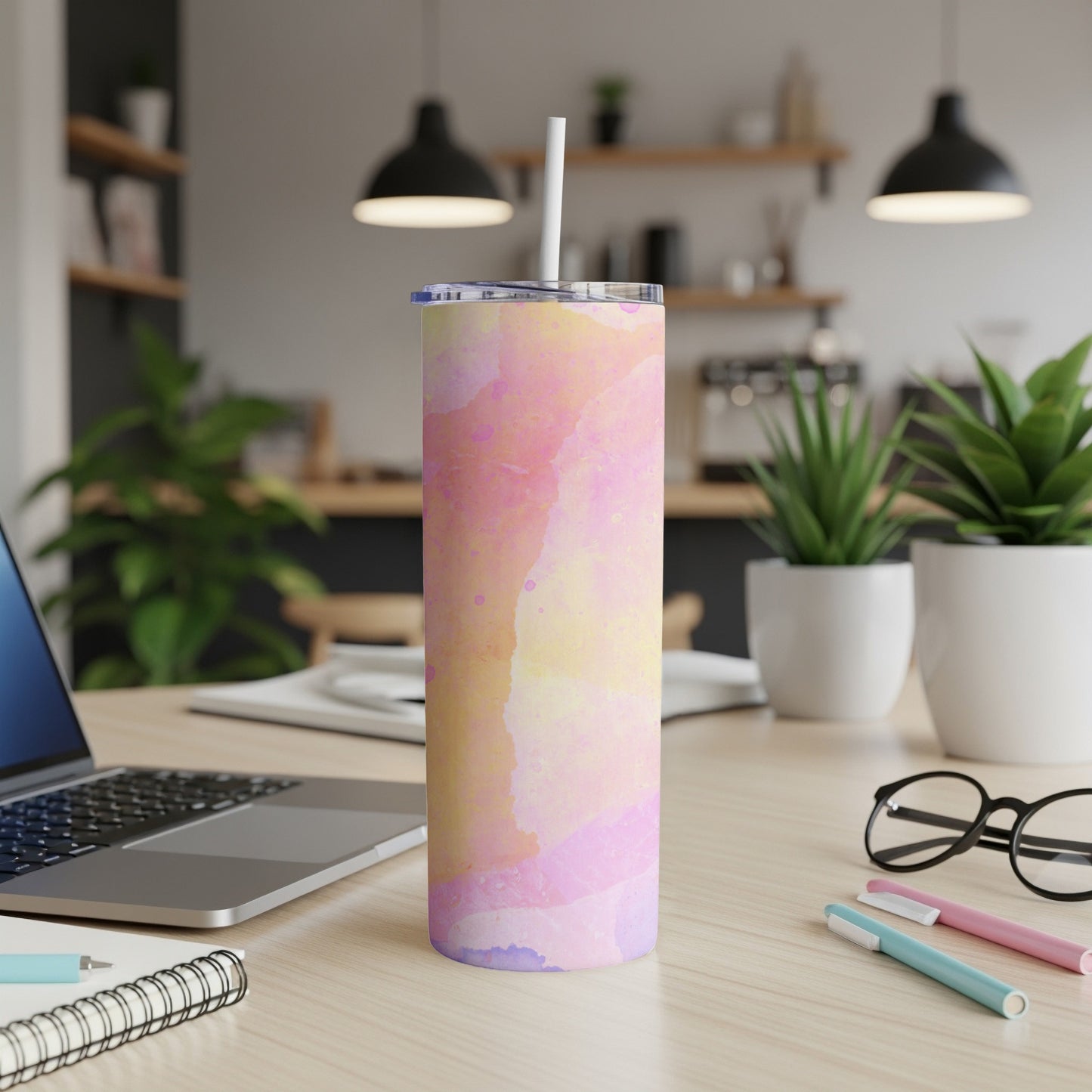 Pink and yellow watercolor tumbler with straw on desk.