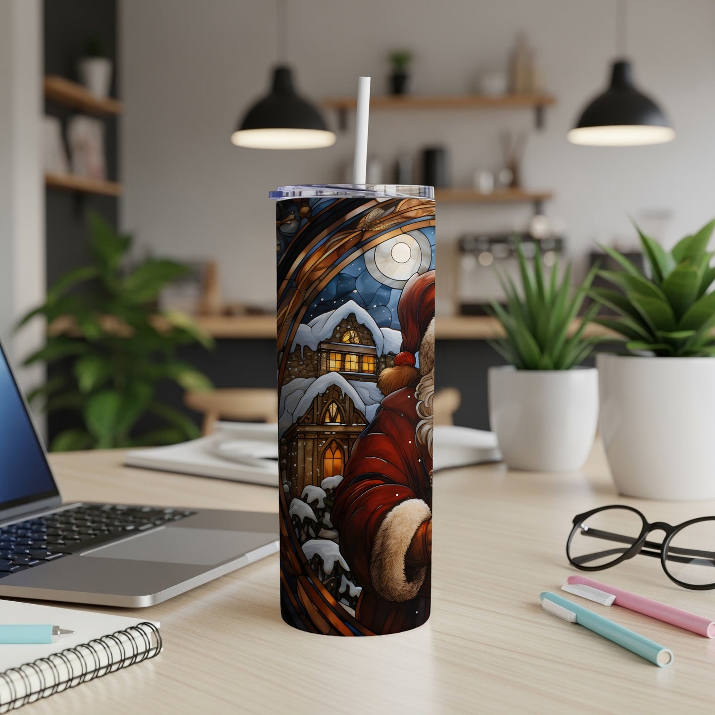 Santa Claus in a snowy village, on a tumbler next to a laptop.