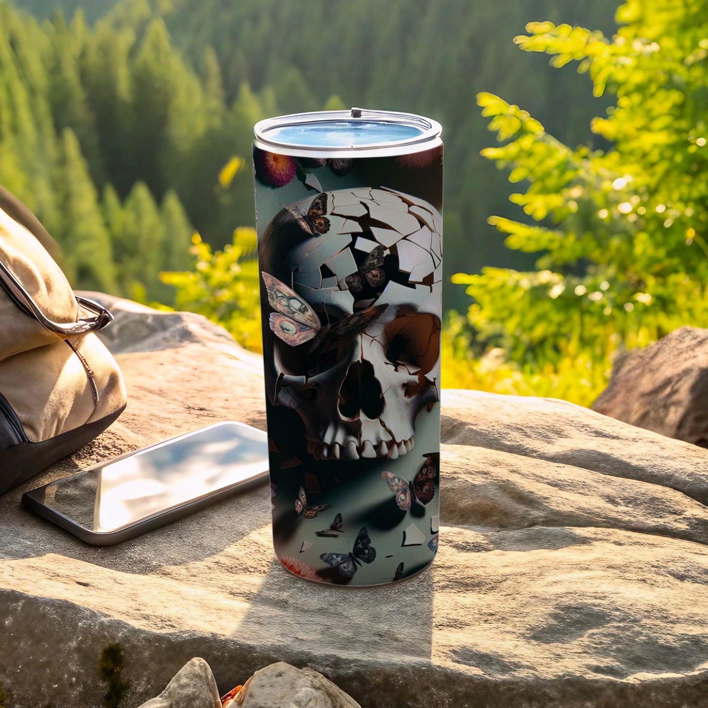 Tall tumbler with skull and butterfly design on a rock.