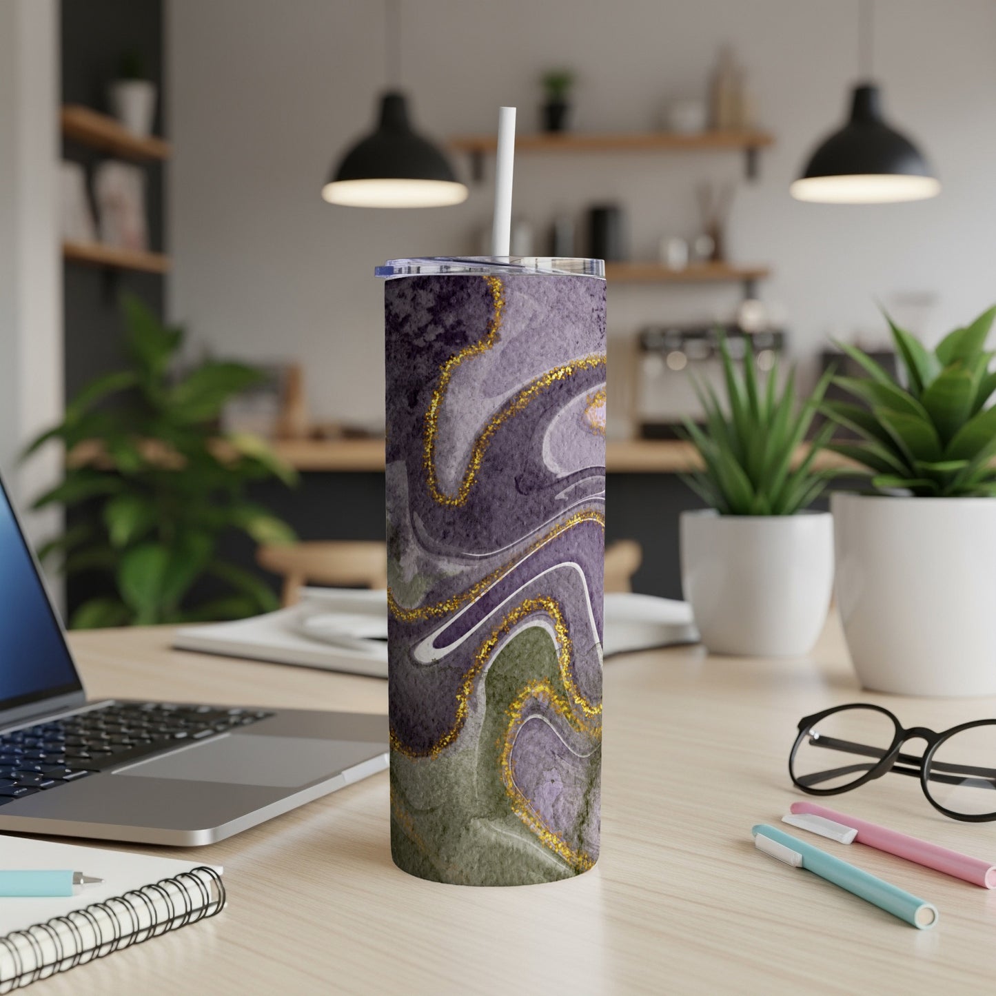 Purple and green marbled tumbler with gold accents, on a desk.
