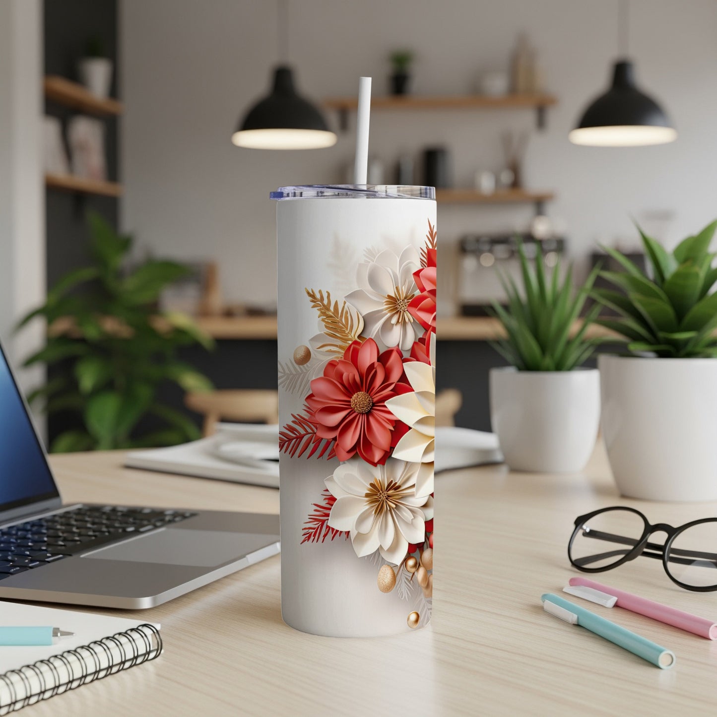 White tumbler with red and cream floral design on desk.