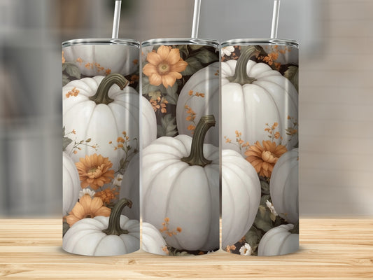 White pumpkins with orange flowers on a tumbler.