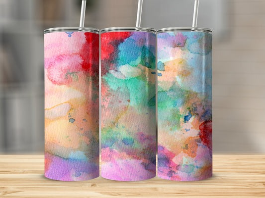 Three tumblers with colorful watercolor designs stand on a wooden surface.