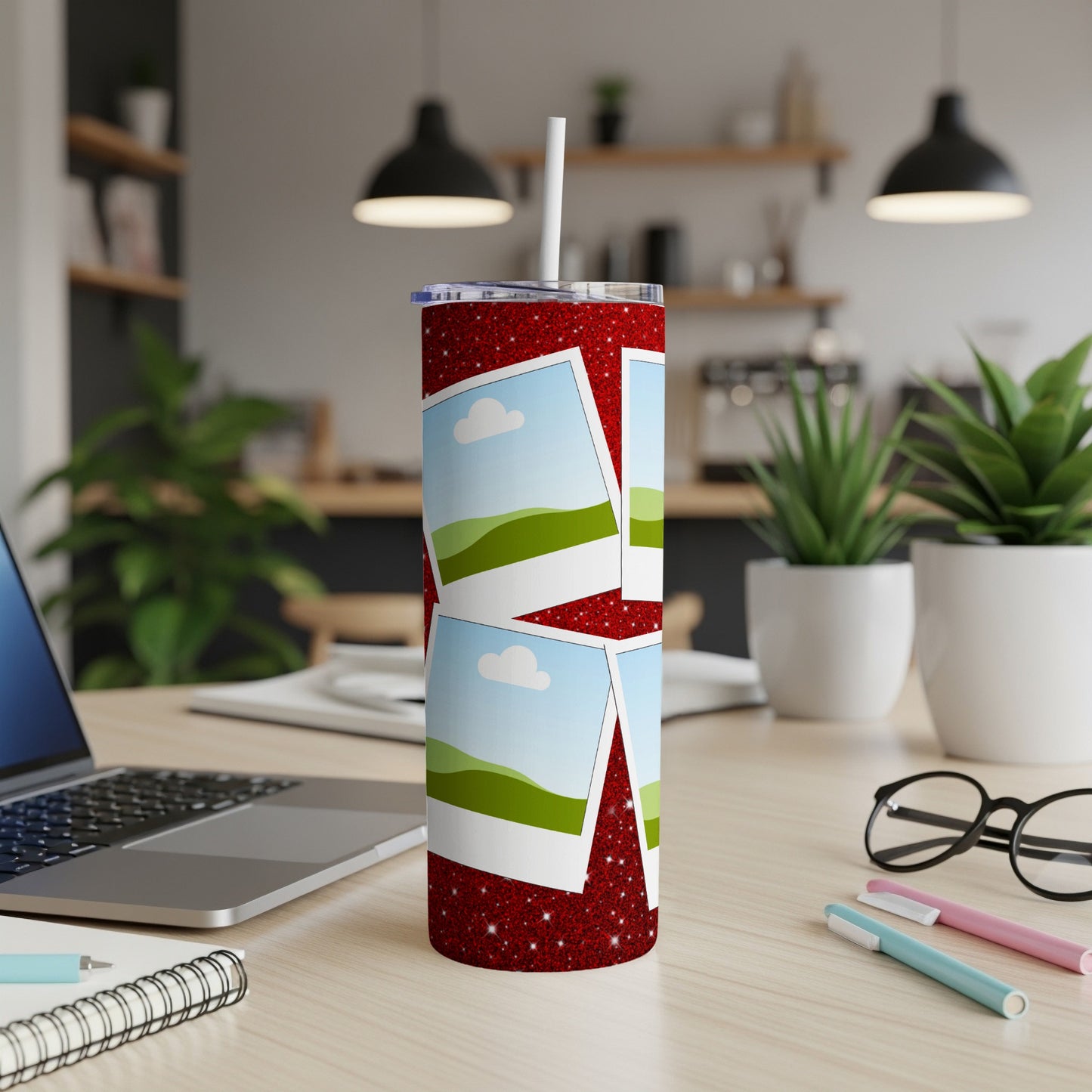 Red glitter tumbler with scattered photos of landscape scenes and a white straw.