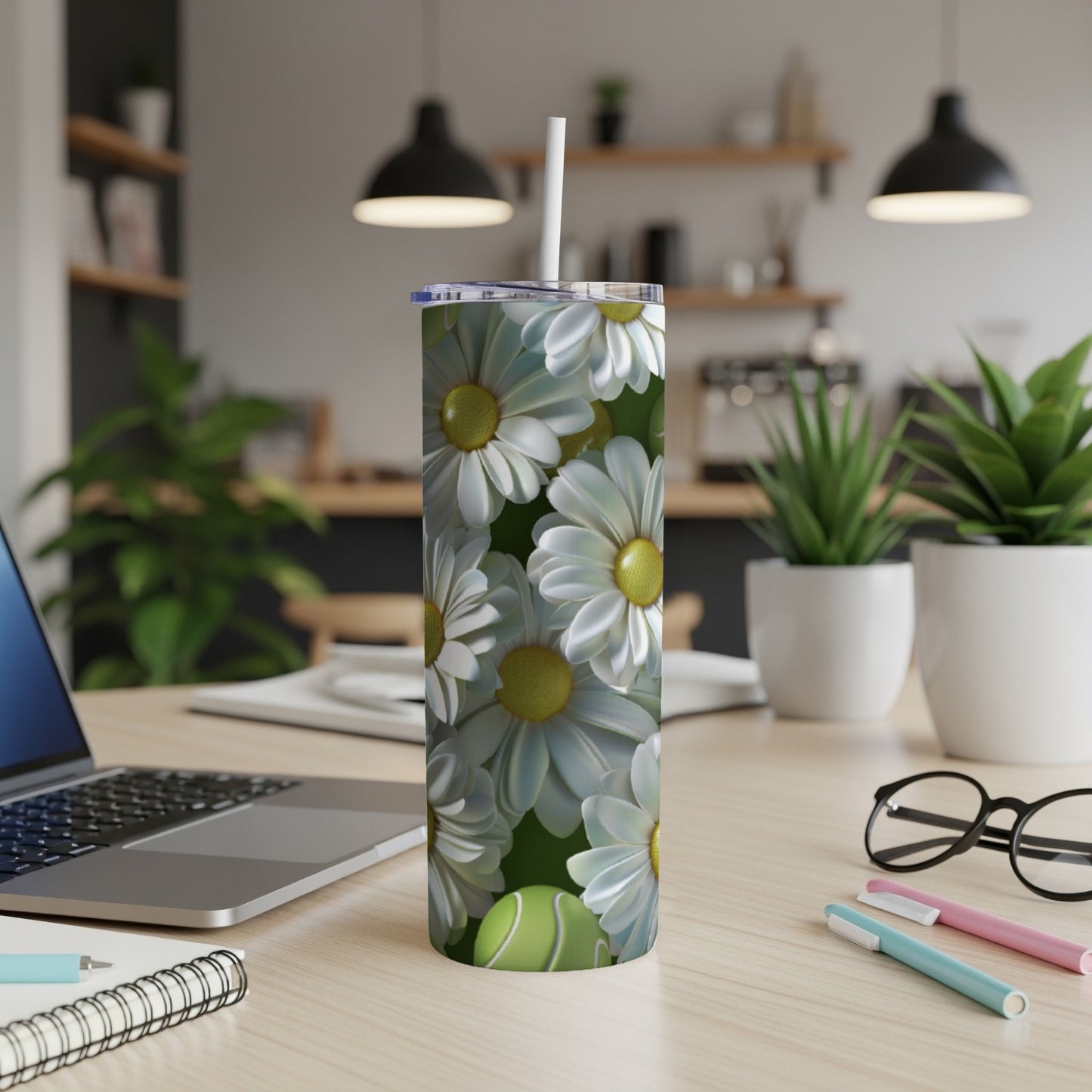 White daisy pattern on a tumbler with a straw, resting on a desk.