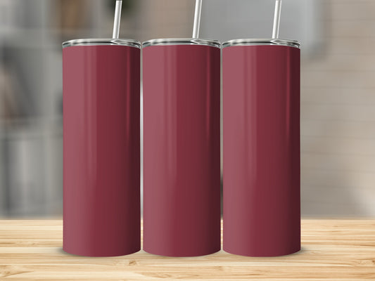 Three maroon tumblers with white straws stand on a wooden surface.