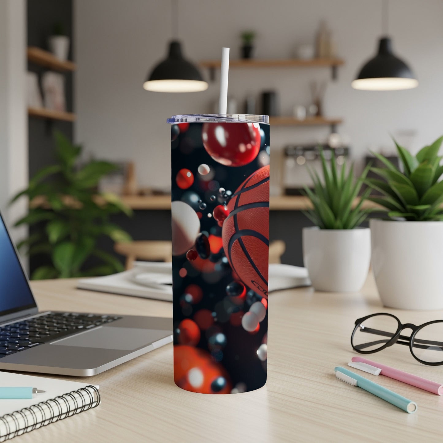 Basketball pattern on a tumbler with a straw on a desk.