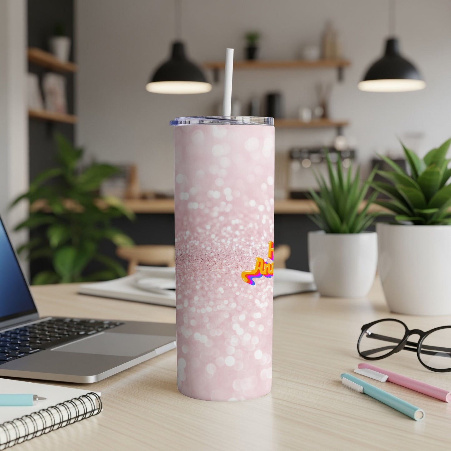 Pink glitter tumbler with "Amazing" text, sitting on a desk.